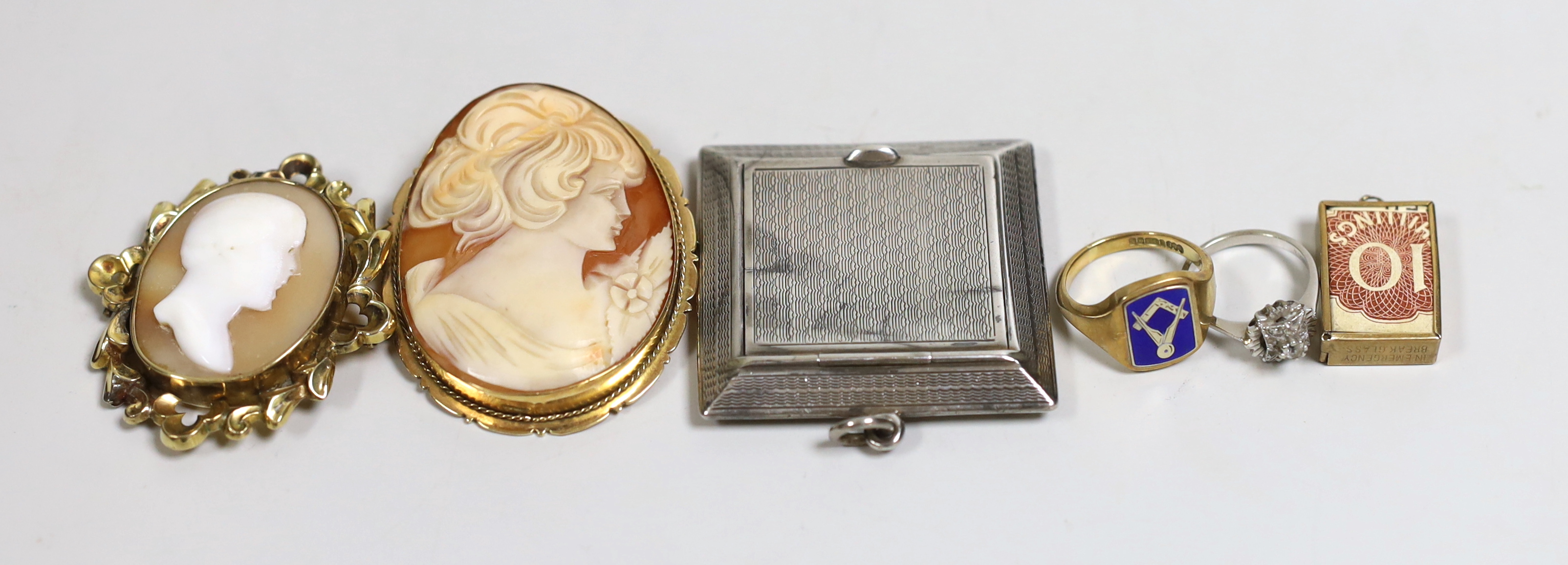 An early 1960's 9ct gold and enamel masonic ring, size P, a 9ct gold mounted oval cameo shell brooch, one other cameo brooch, a 9ct gold mounted charm, an 18ct white metal and diamond chip ring and a silver compact (lack